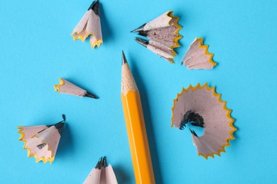 Photo of Graphite pencil and shavings on light blue background, top view. Macro photo