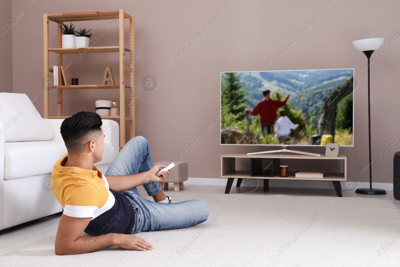 Photo of Man watching television at home. Living room interior with TV on stand