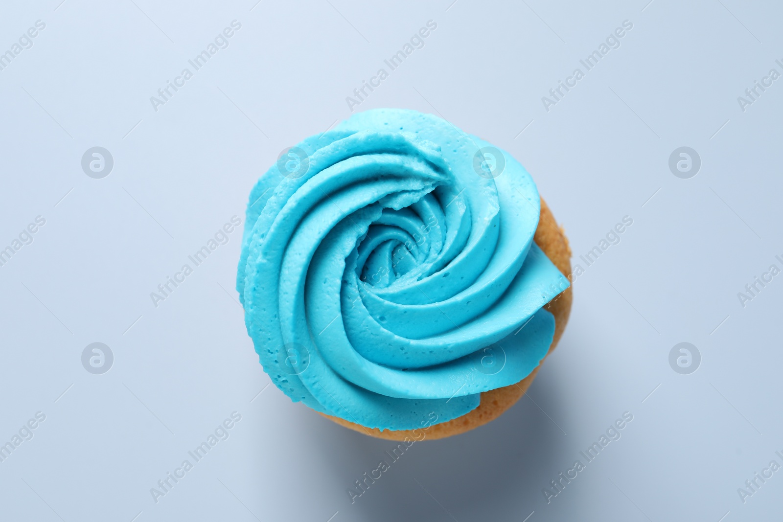 Photo of Delicious cupcake with bright cream on light background, top view