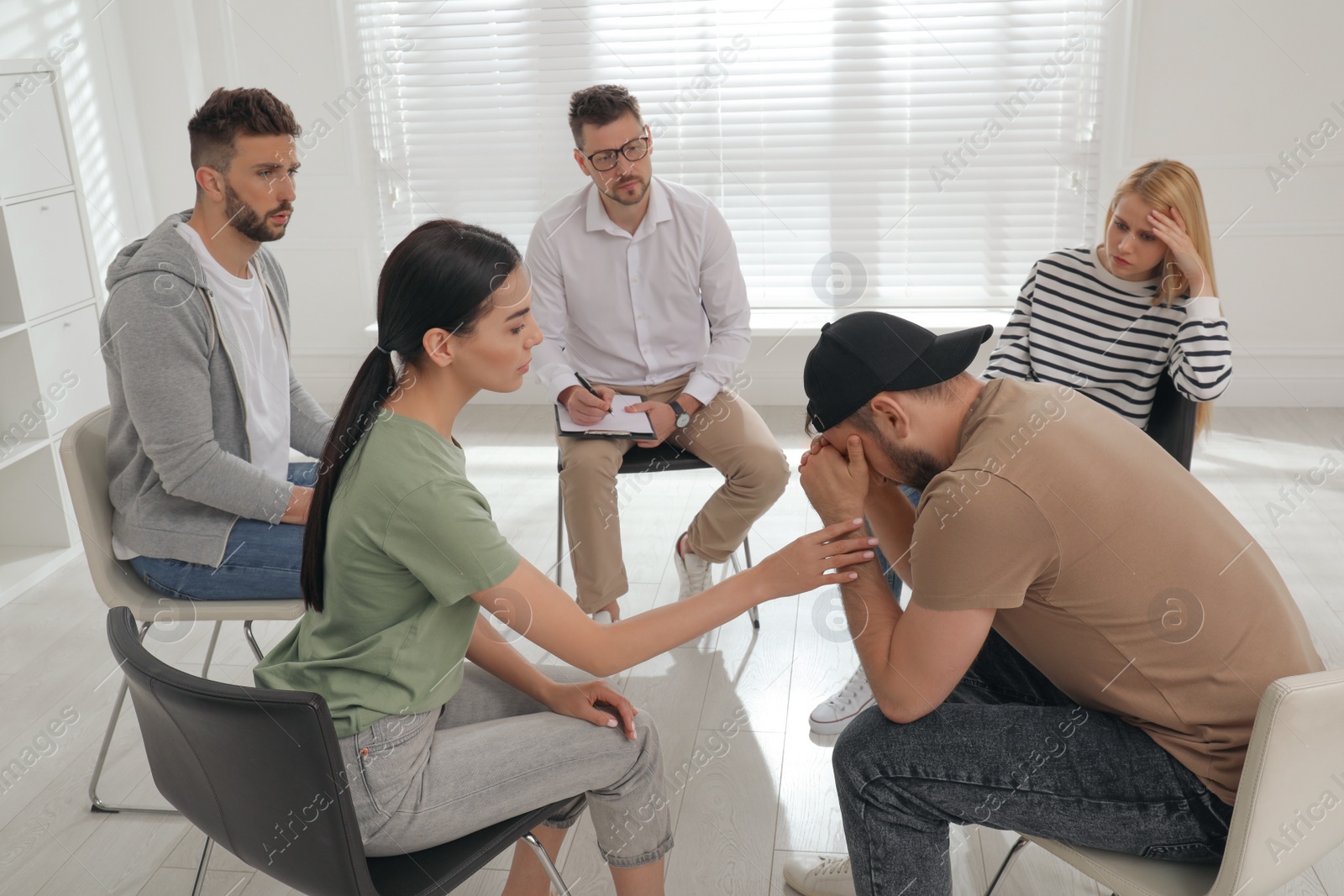 Photo of Psychotherapist working with group of drug addicted people at therapy session indoors