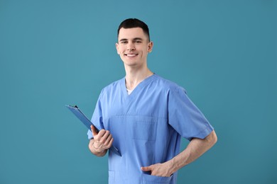 Portrait of smiling medical assistant with clipboard on light blue background