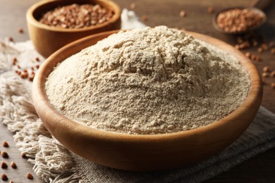 Photo of Bowl of buckwheat flour and cloth on wooden table