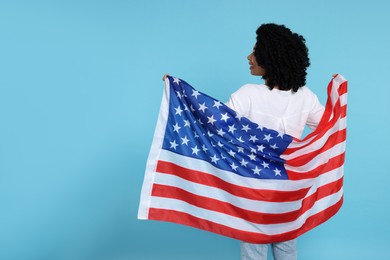 4th of July - Independence Day of USA. Happy woman with American flag on light blue background, back view. Space for text