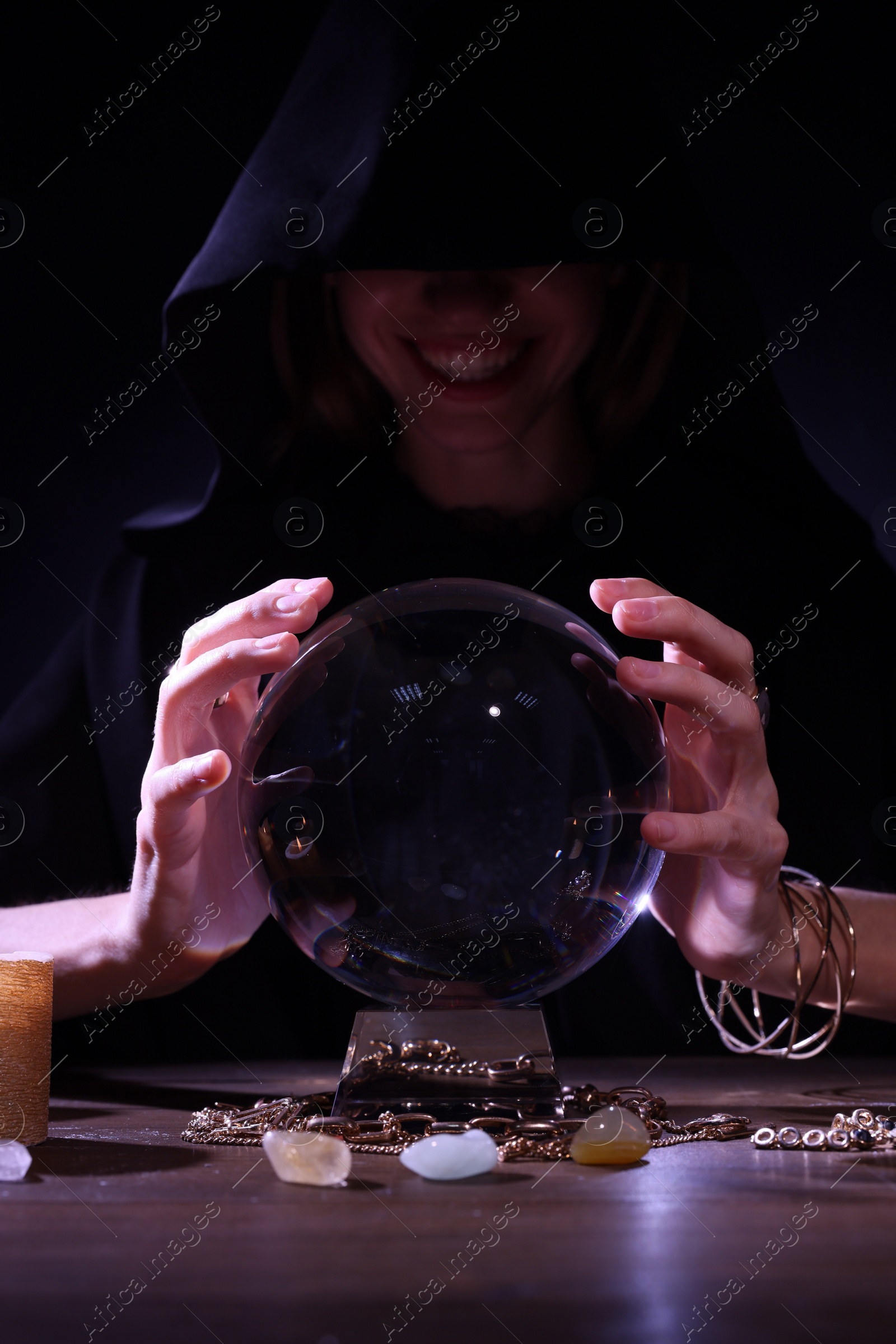 Photo of Soothsayer using crystal ball to predict future at table in darkness. Fortune telling