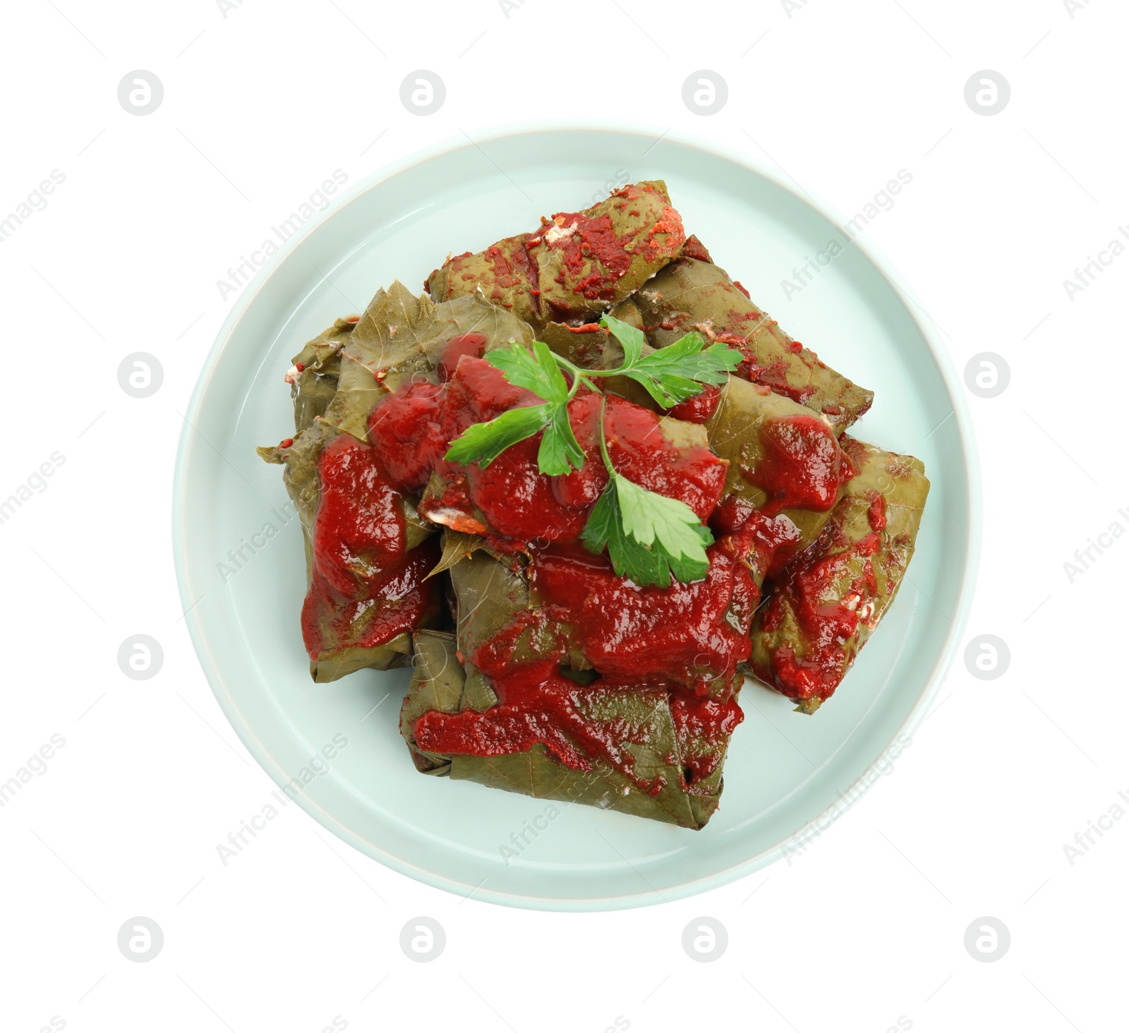 Photo of Plate of delicious stuffed grape leaves with tomato sauce and parsley isolated on white, top view