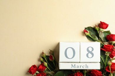 Photo of Wooden block calendar with date 8th of March and roses on beige background, flat lay. Space for text