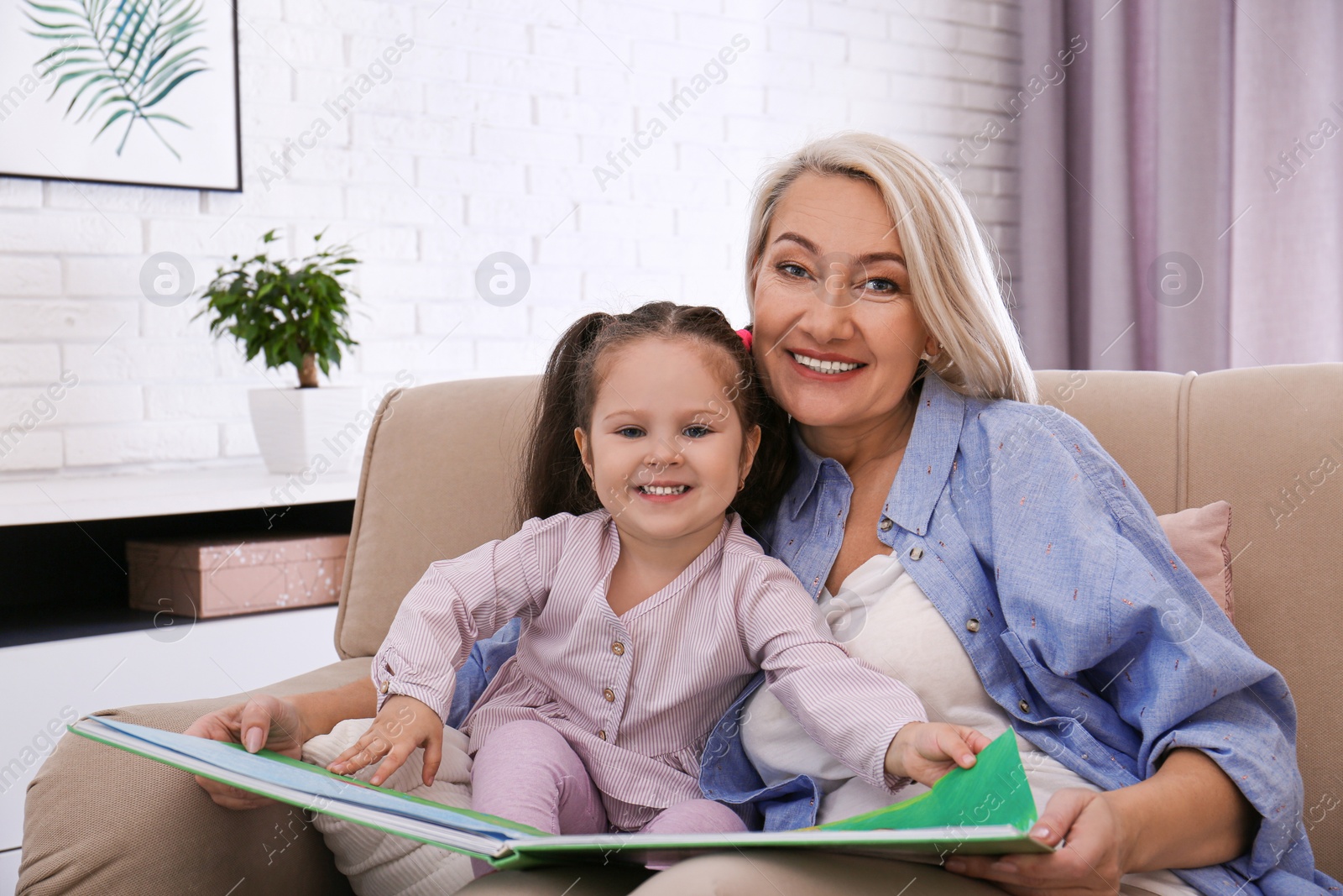 Photo of Granddaughter and grandmother reading book at home