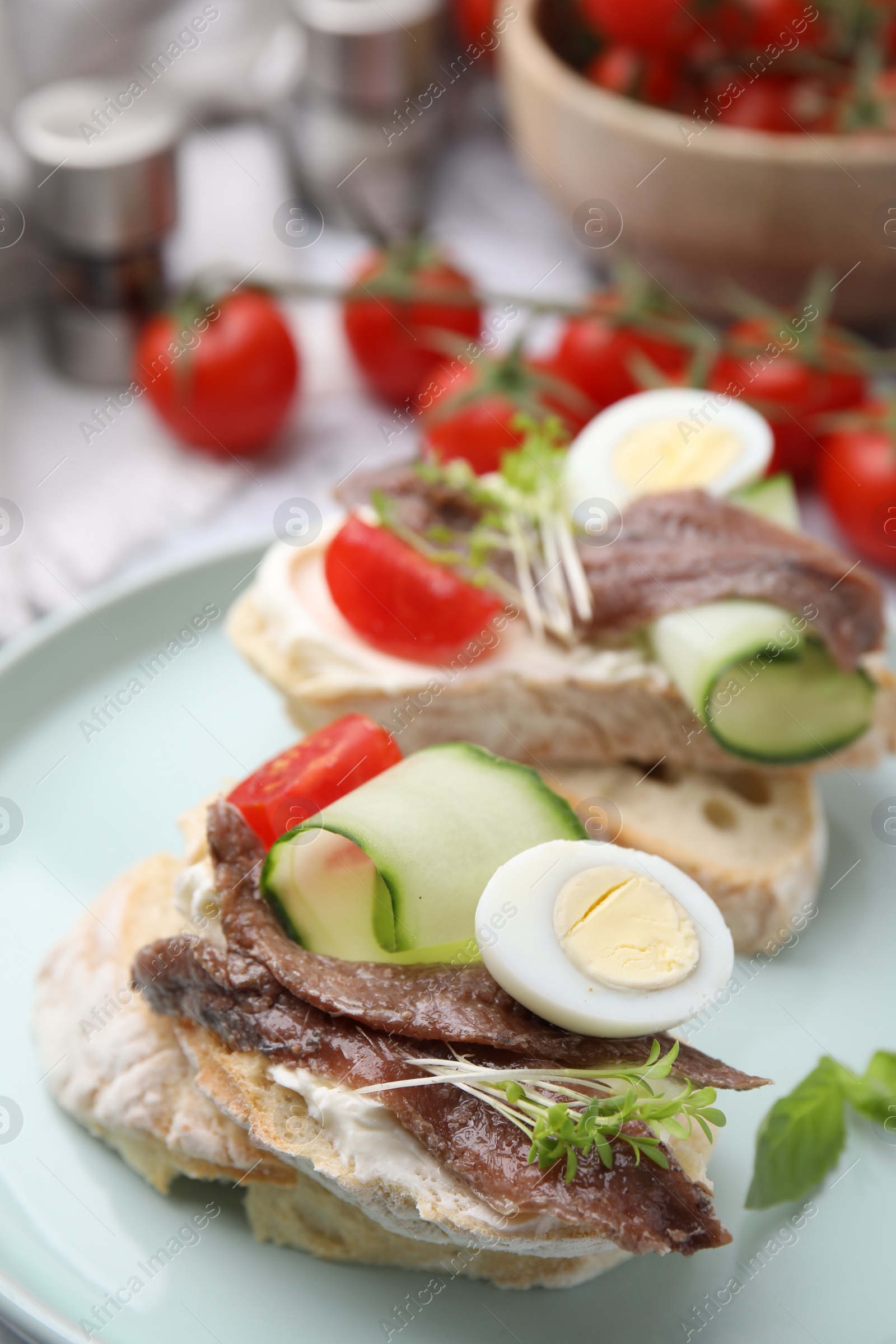 Photo of Delicious bruschettas with anchovies, tomato, cucumber, egg and cream cheese on plate, closeup