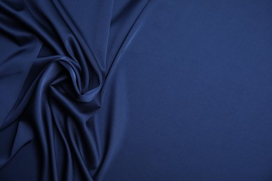 Photo of Crumpled dark blue silk fabric as background, top view. Space for text