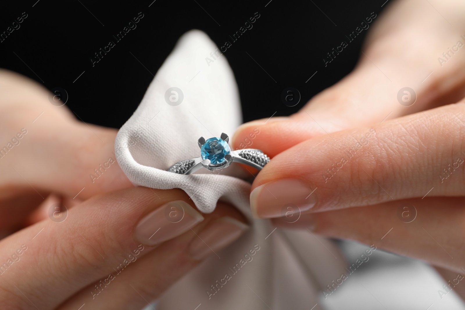 Photo of Jeweler cleaning topaz ring with microfiber cloth, closeup