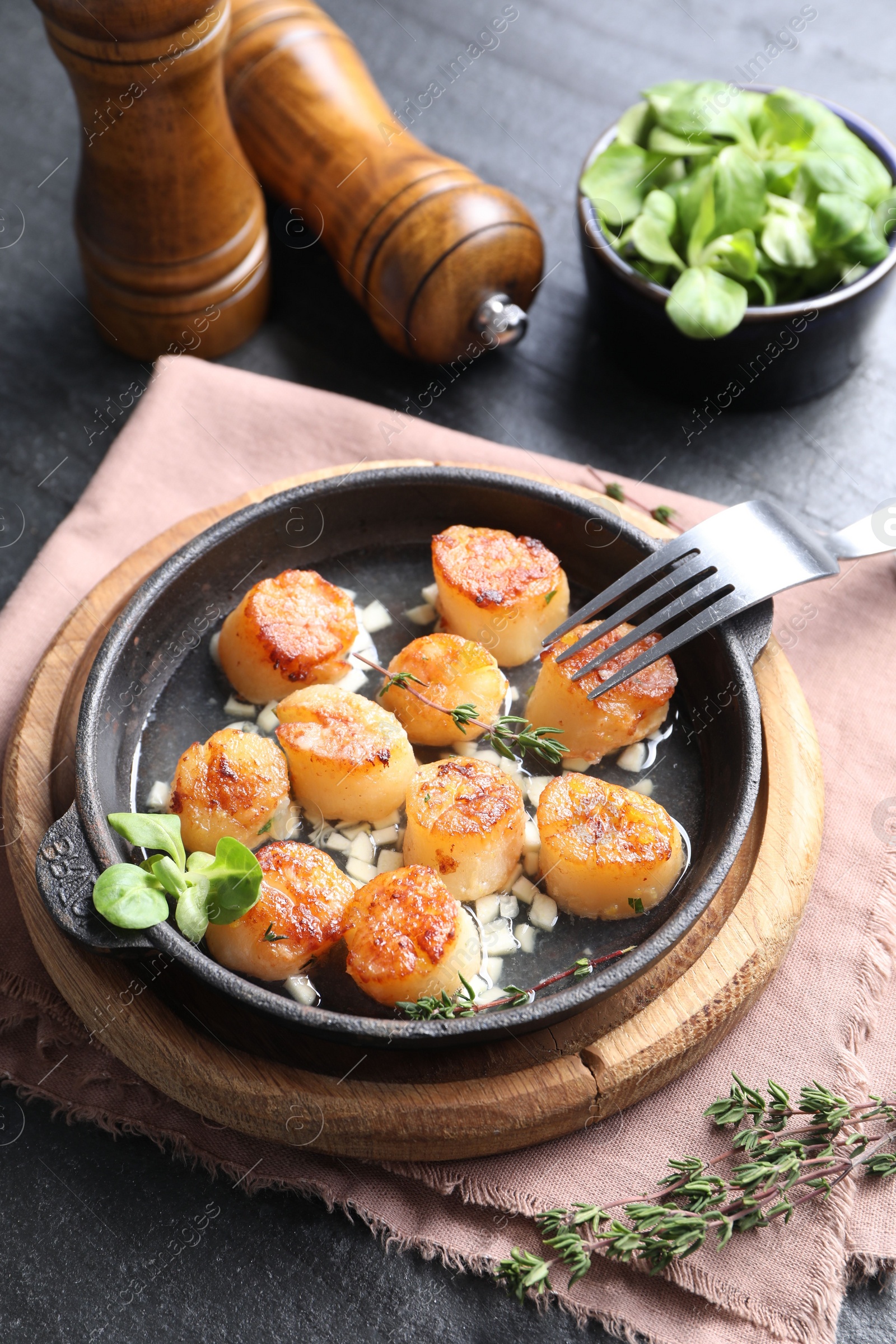 Photo of Delicious fried scallops in dish served on dark gray textured table