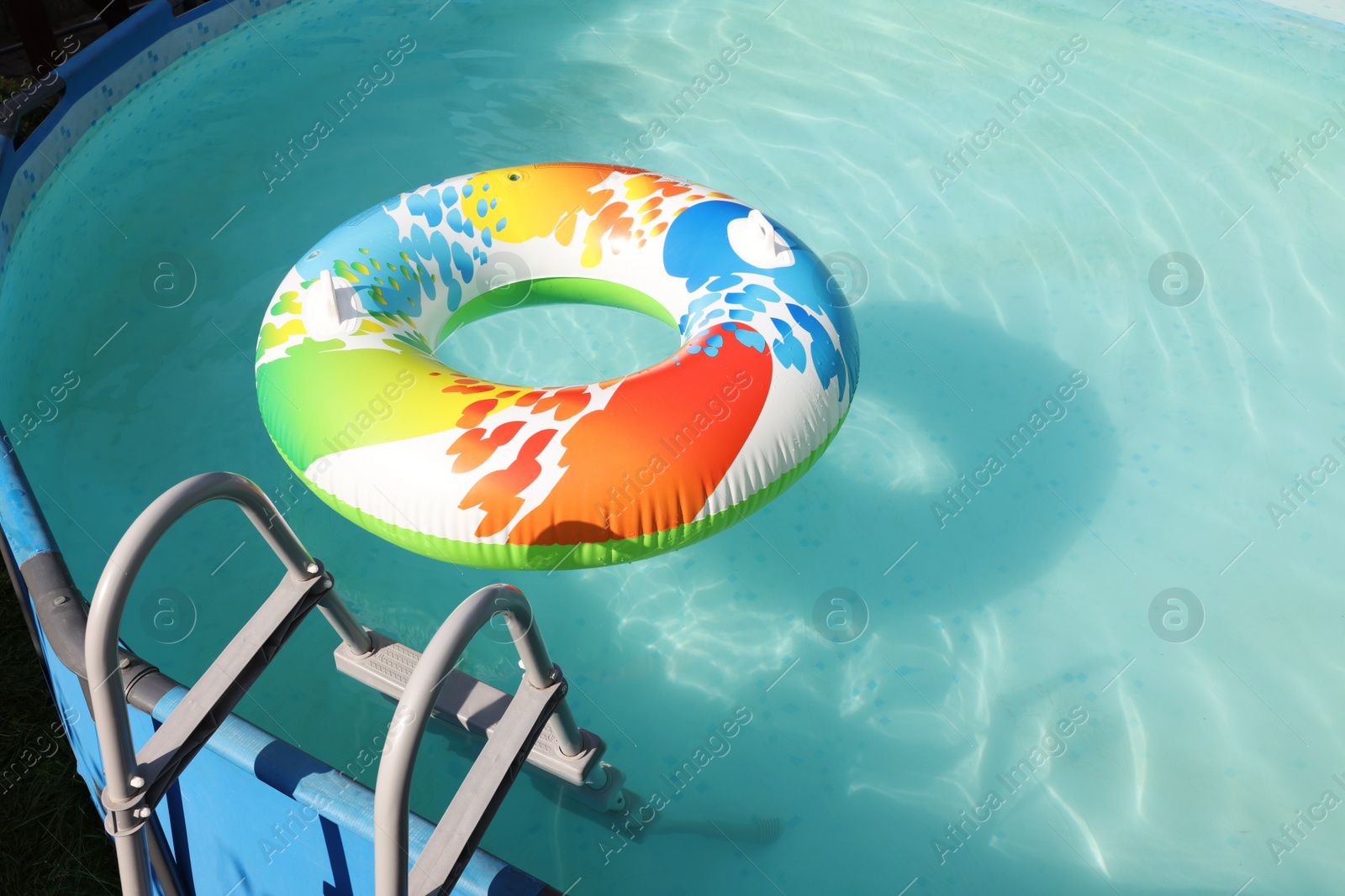 Photo of Inflatable ring floating on water in above ground swimming pool outdoors