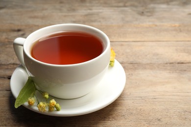 Cup of tea and linden blossom on wooden table. Space for text