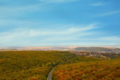 Image of Aerial view of road and beautiful autumn forest near village