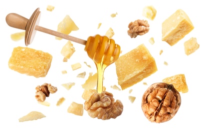 Pieces of delicious parmesan, walnuts and honey falling on white background