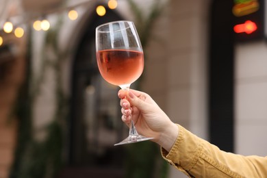 Photo of Woman holding glass of rose wine outdoors, closeup