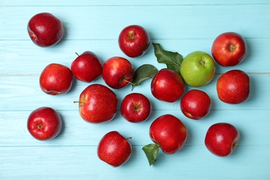 Photo of Green apple among red ones on wooden background, top view. Be different