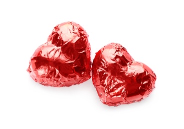 Heart shaped chocolate candies in red foil on white background, top view