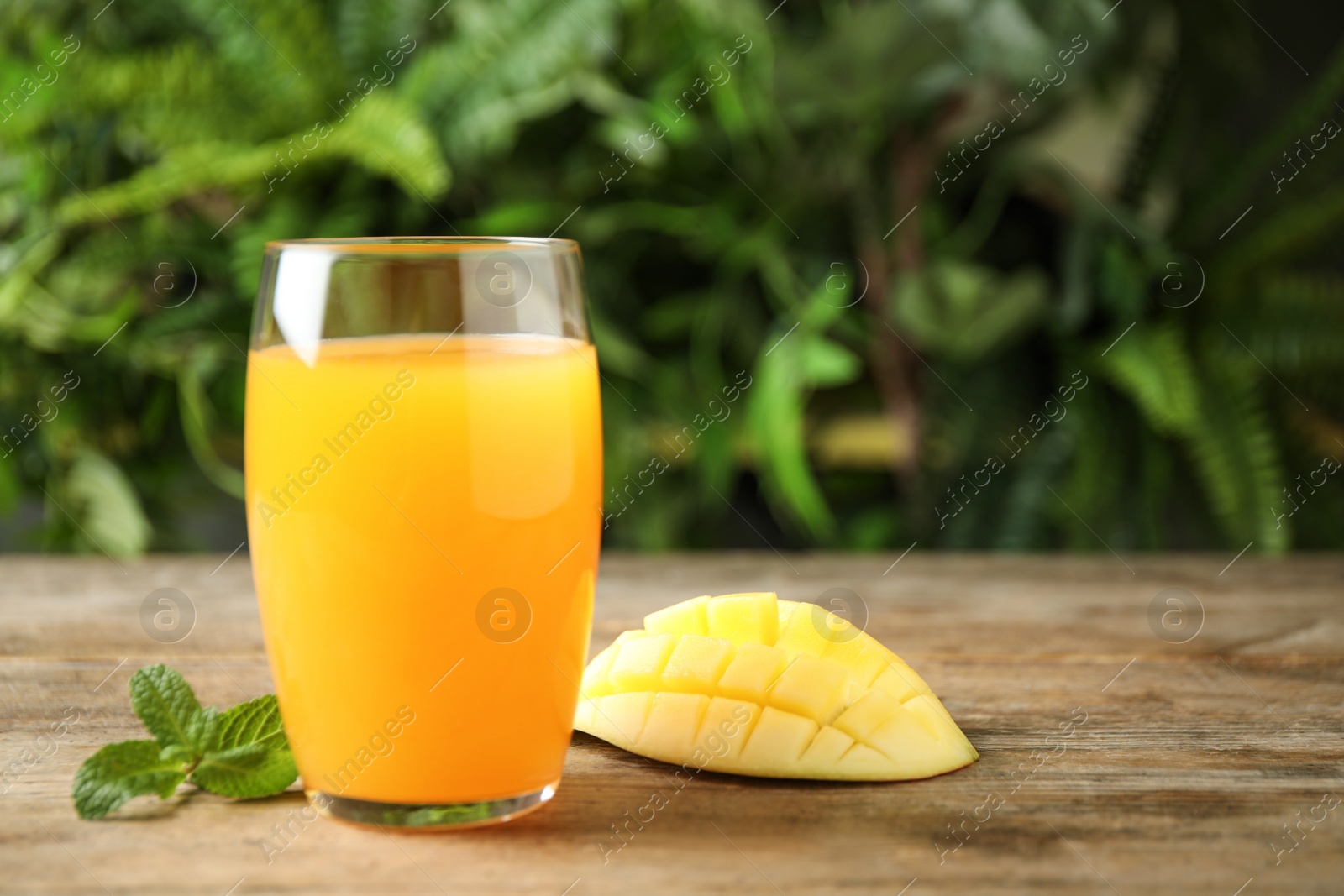 Photo of Fresh delicious mango drink on wooden table. Space for text