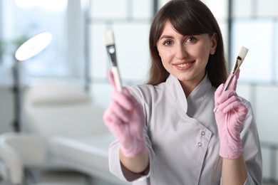 Photo of Cosmetologist with cosmetic brushes in clinic, selective focus. Space for text
