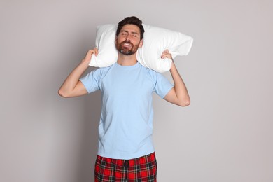 Photo of Sleepy handsome man with soft pillow on light grey background