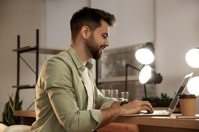 Photo of Man working with laptop at table in cafe