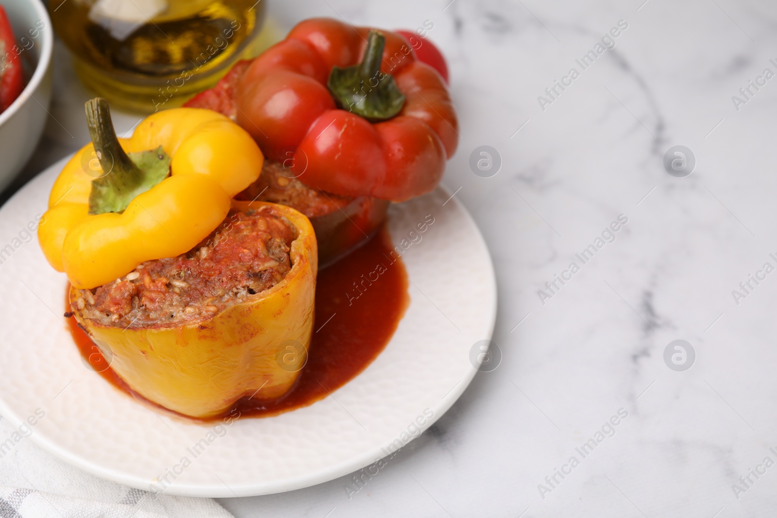 Photo of Delicious stuffed bell peppers served on white marble table. Space for text