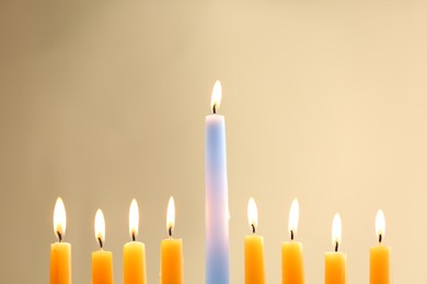 Photo of Hanukkah celebration. Burning candles on beige background, closeup