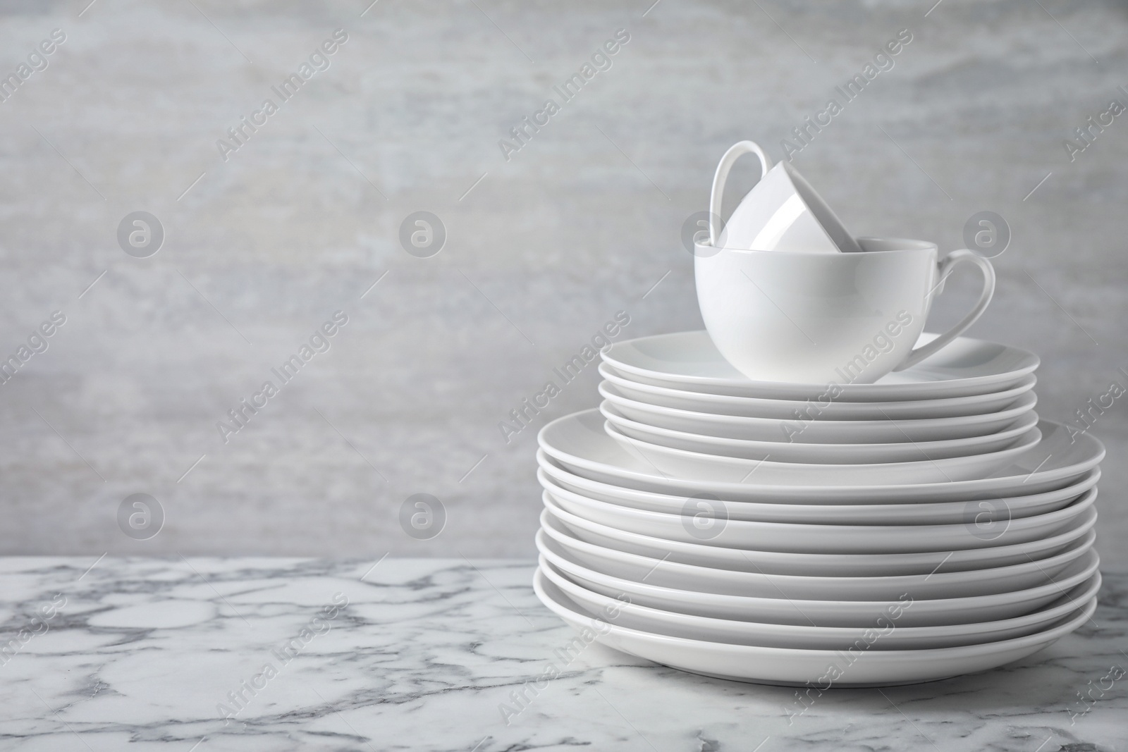 Photo of Set of clean dishware on marble table. Space for text