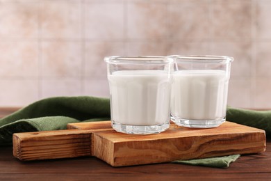 Photo of Glasses of tasty milk on wooden table, space for text