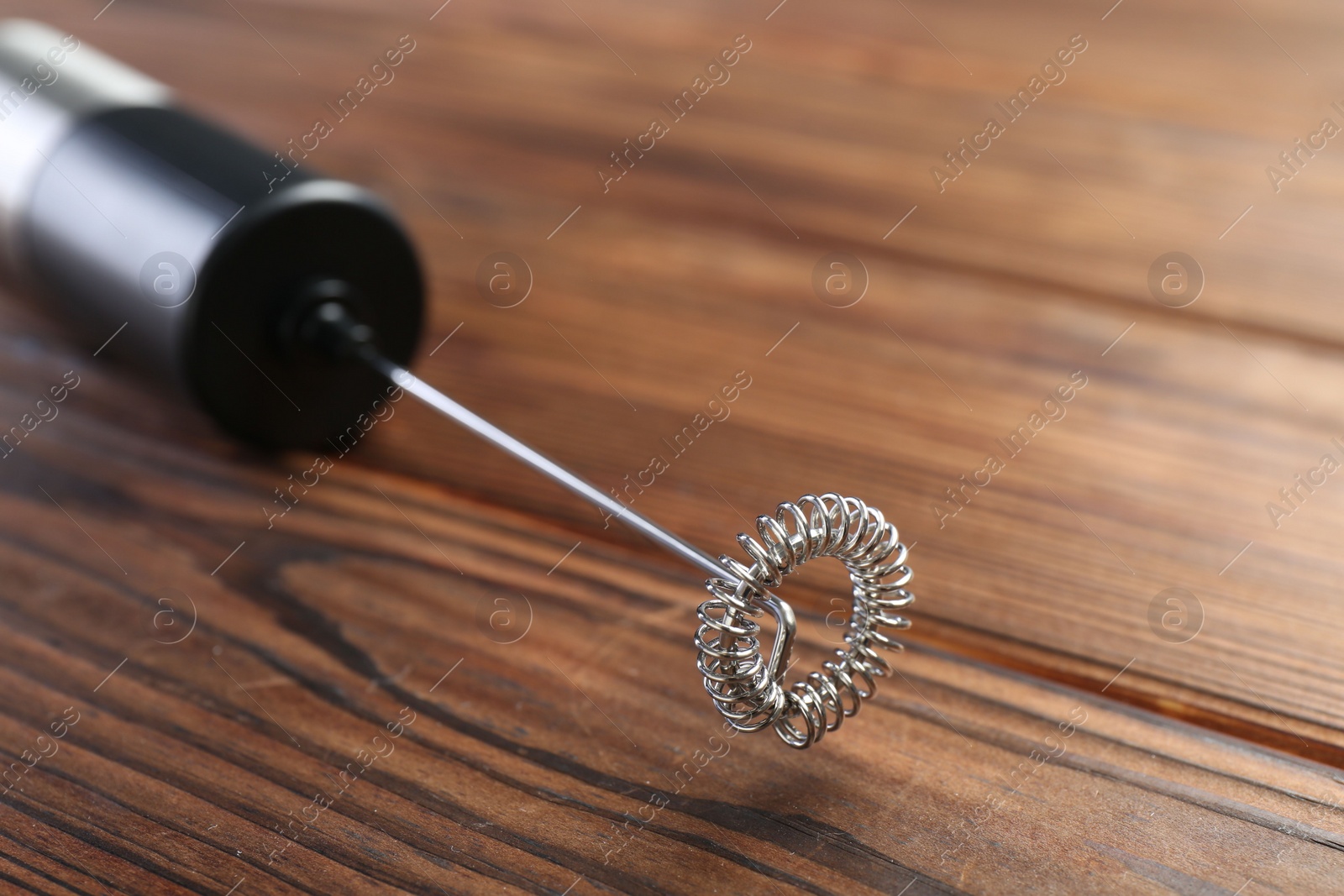 Photo of Black milk frother wand on wooden table, closeup. Space for text