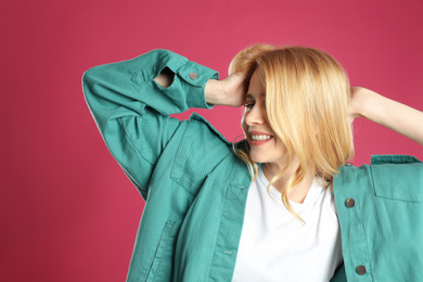 Portrait of beautiful young woman with dyed long hair on pink background