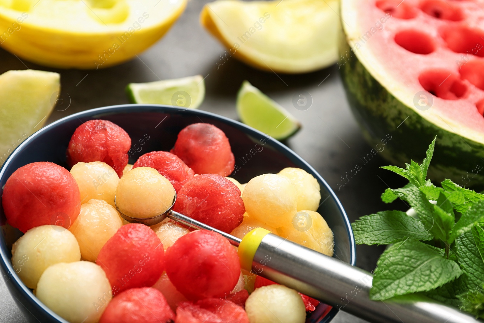 Photo of Bowl of melon and watermelon balls with scoop on table, closeup