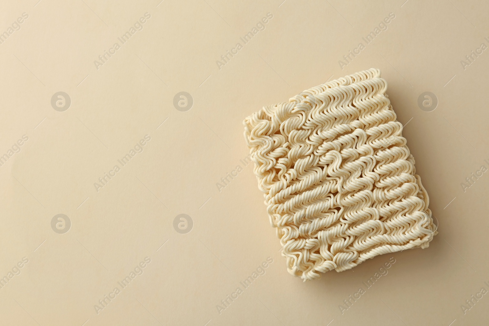 Photo of Block of quick cooking noodles on color background, top view. Space for text