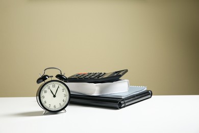 Photo of Alarm clock and office stationery on white table against beige background, space for text. Time management