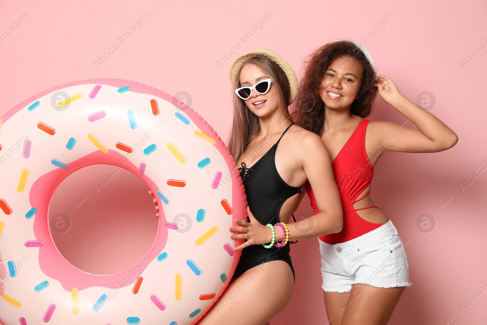 Photo of Beautiful young women in beachwear with inflatable ring on color background