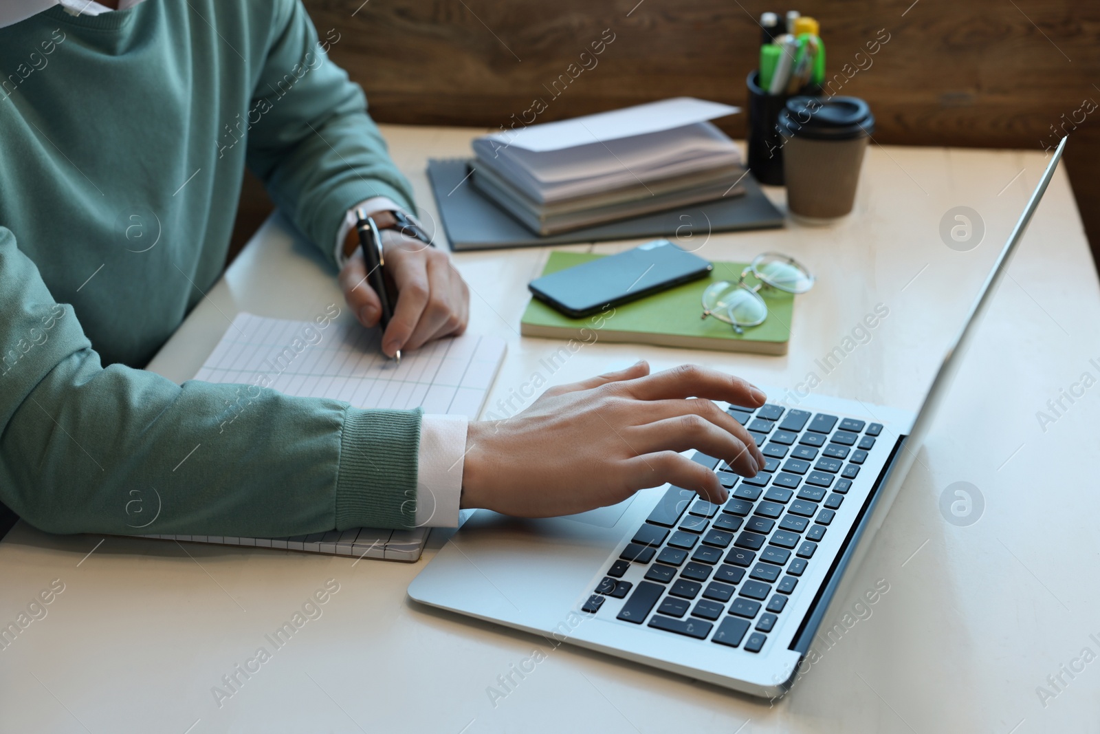 Photo of Male student with laptop studying at table in cafe, closeup