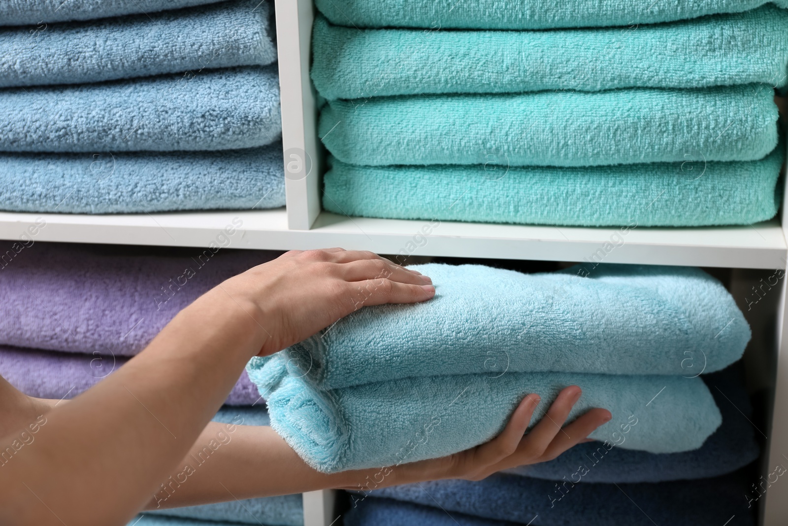 Photo of Woman putting towels on shelf, closeup view