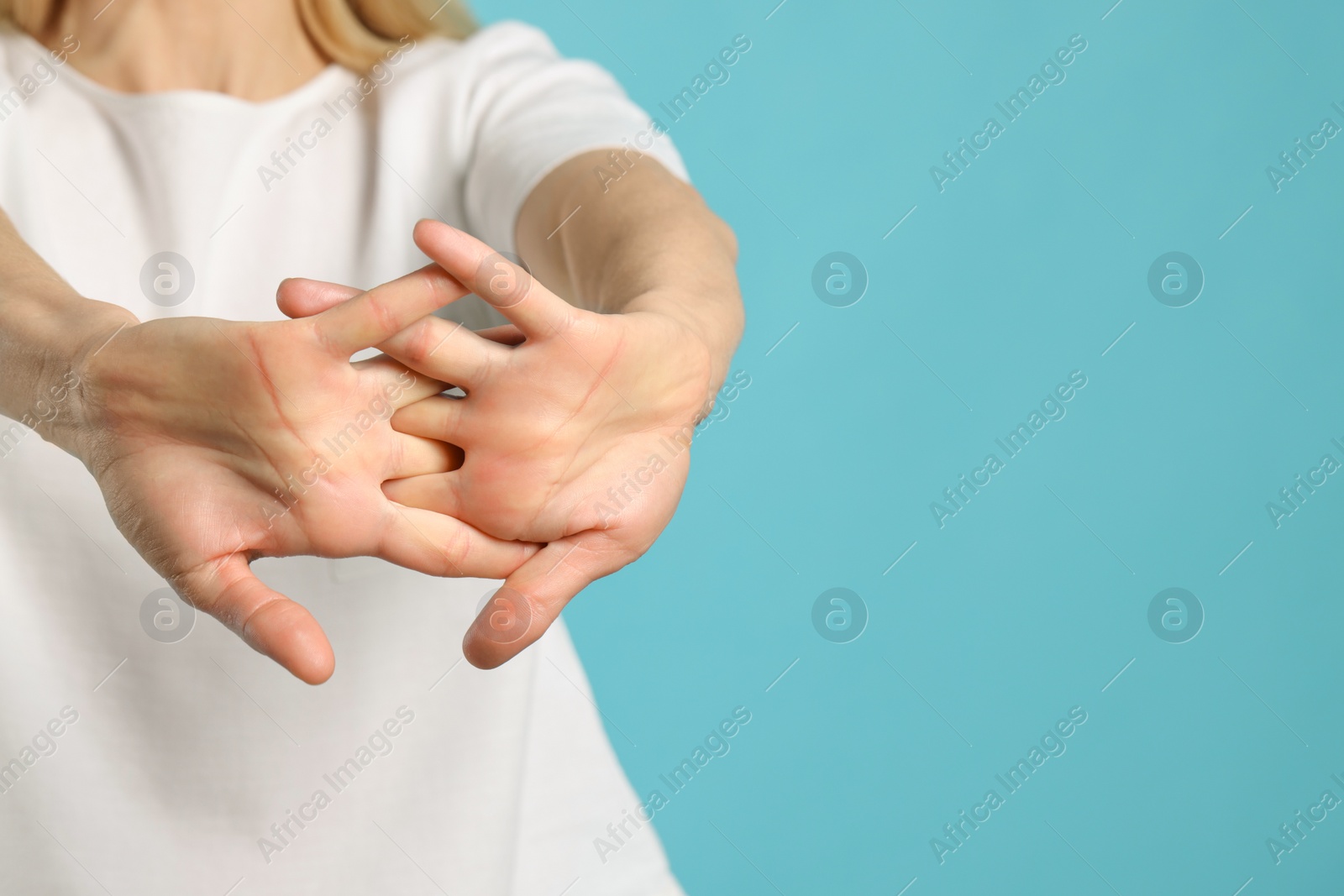 Photo of Woman cracking her knuckles on turquoise background, closeup and space for text. Bad habit