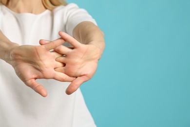 Woman cracking her knuckles on turquoise background, closeup and space for text. Bad habit