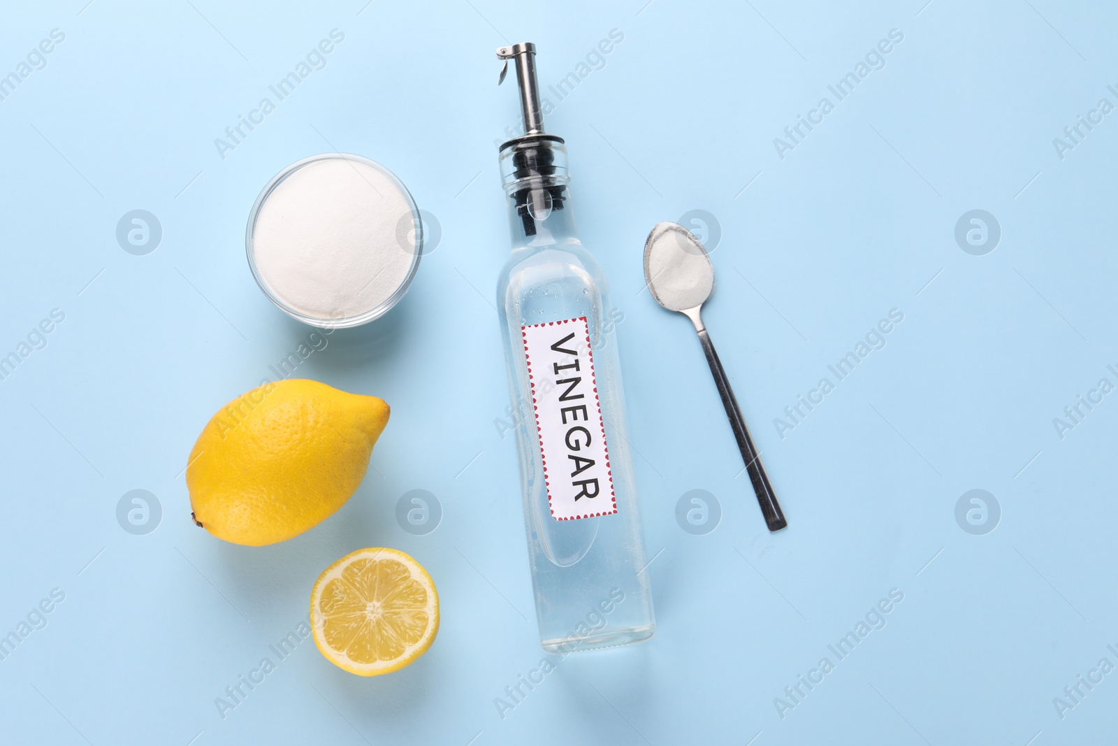 Photo of Eco friendly natural cleaners. Vinegar in bottle, soda and lemons on light blue background, flat lay