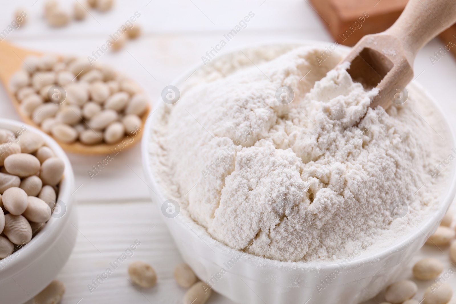 Photo of Kidney bean flour and seeds on white wooden table, closeup