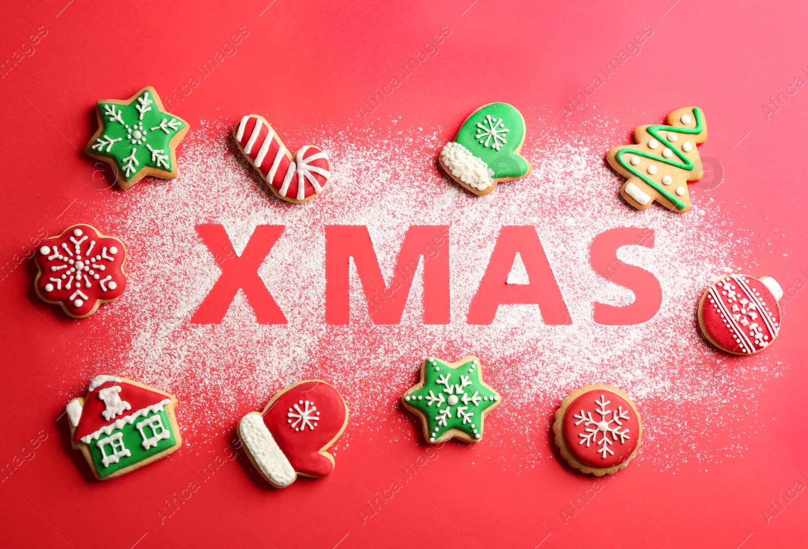 Photo of Flat lay composition with word XMAS made of flour  tasty homemade cookies on red background