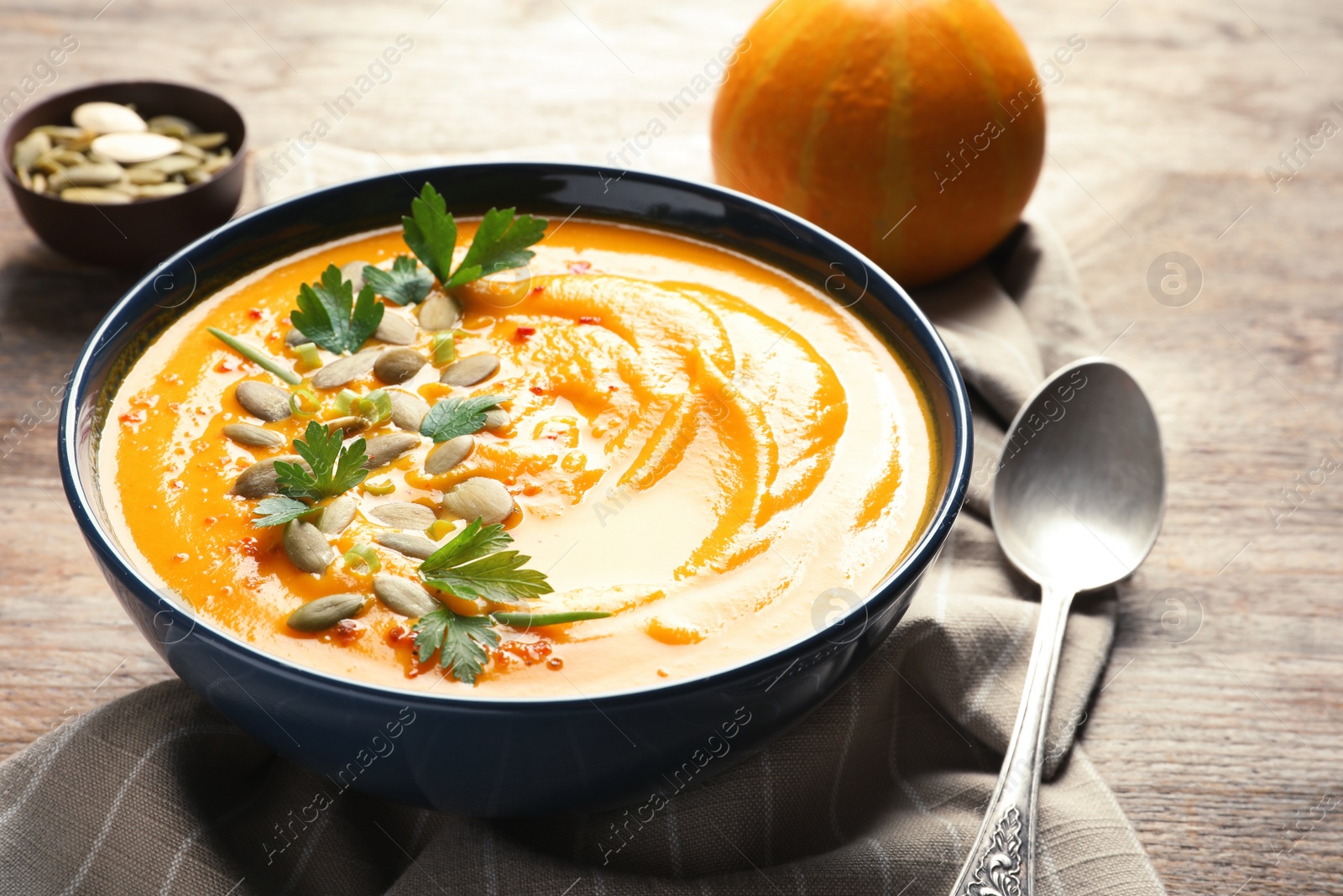 Photo of Delicious pumpkin cream soup in bowl on wooden table