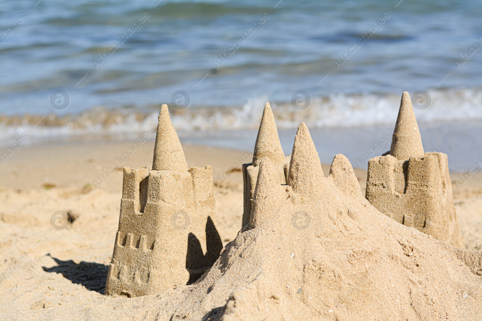 Photo of Beach with sand castle near sea on sunny day