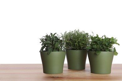 Photo of Pots with thyme, sage and mint on wooden table against white background
