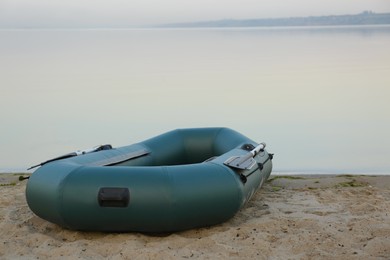 Inflatable rubber fishing boat on sandy beach near river