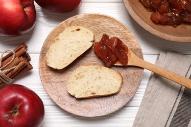 Photo of Delicious apple jam and bread slices on white wooden table, flat lay