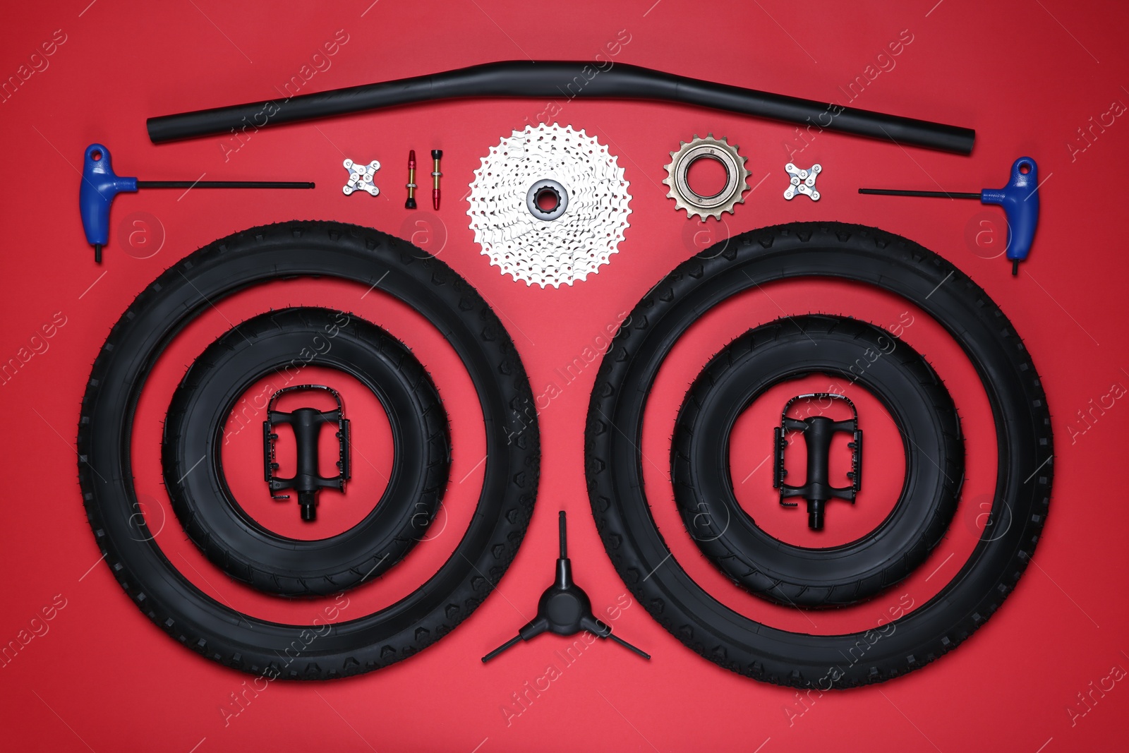 Photo of Set of different bicycle tools and parts on red background, flat lay