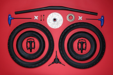 Set of different bicycle tools and parts on red background, flat lay